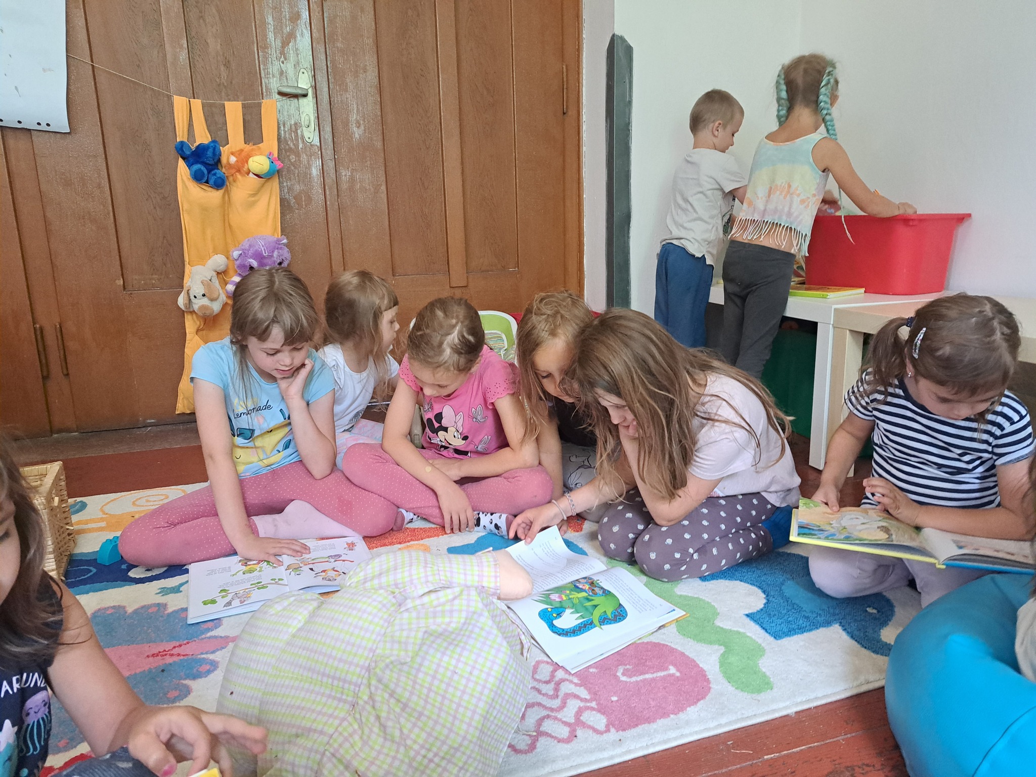 Děti hrají společné hry a čtou si knížky na letním táboře pro nejmenší.