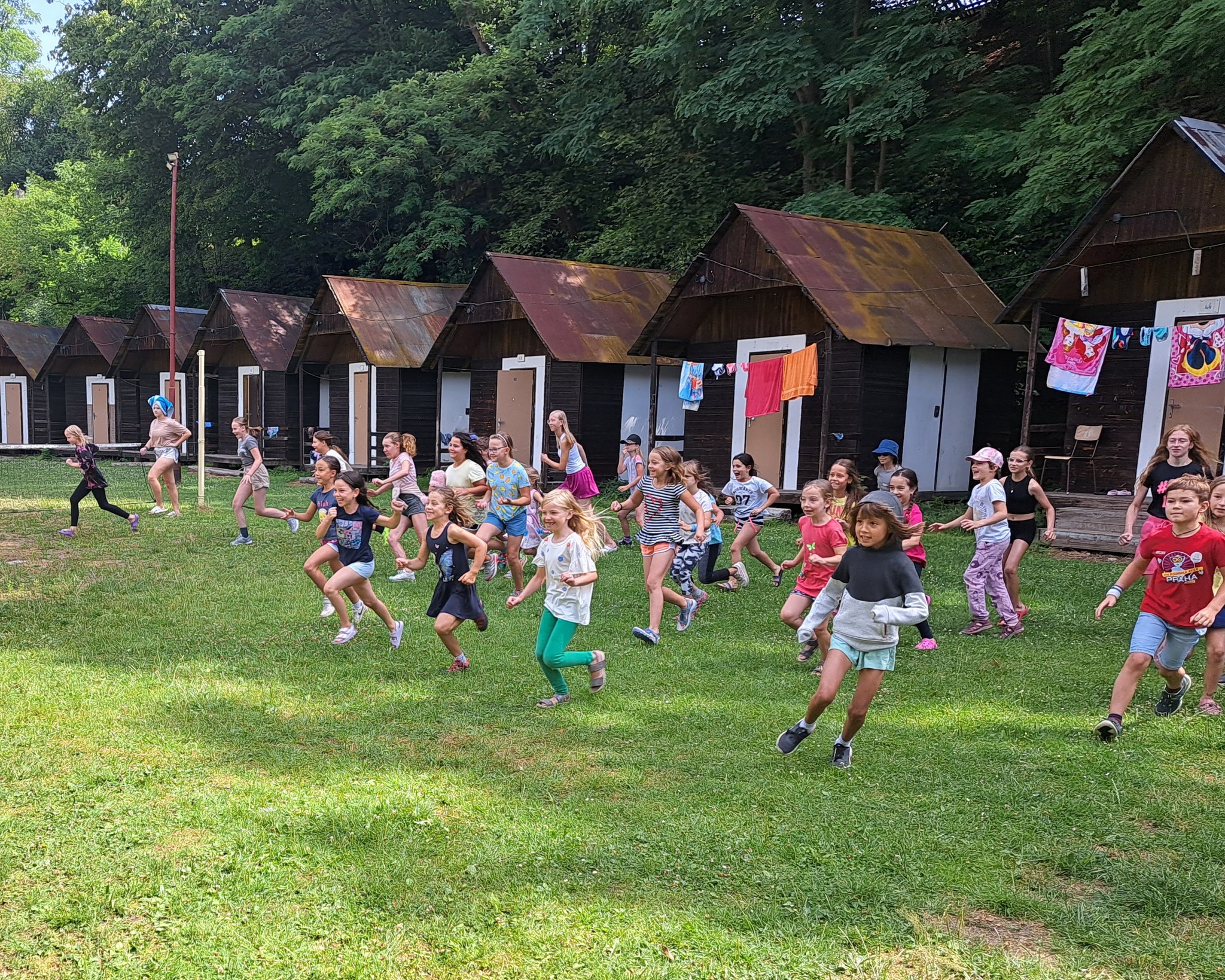 Děti hrají venku pohybové hry na letním dětském táboře.