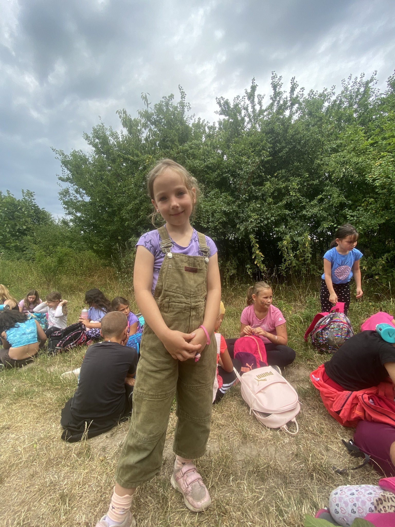 Dívka na letním dětském táboře pózuje v přírodě.