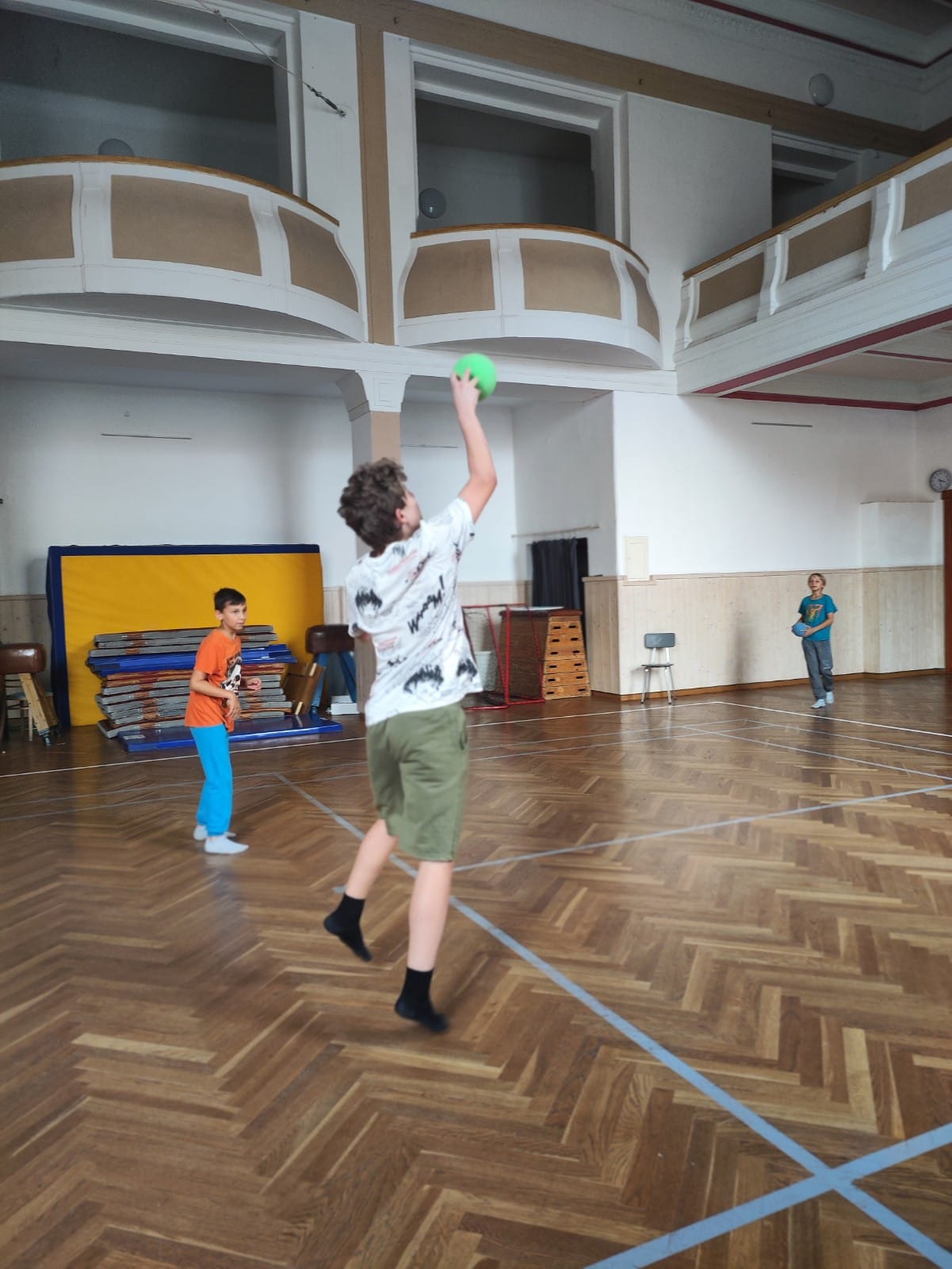 Děti na letním sportovním táboře hrají míčové hry v tělocvičně.