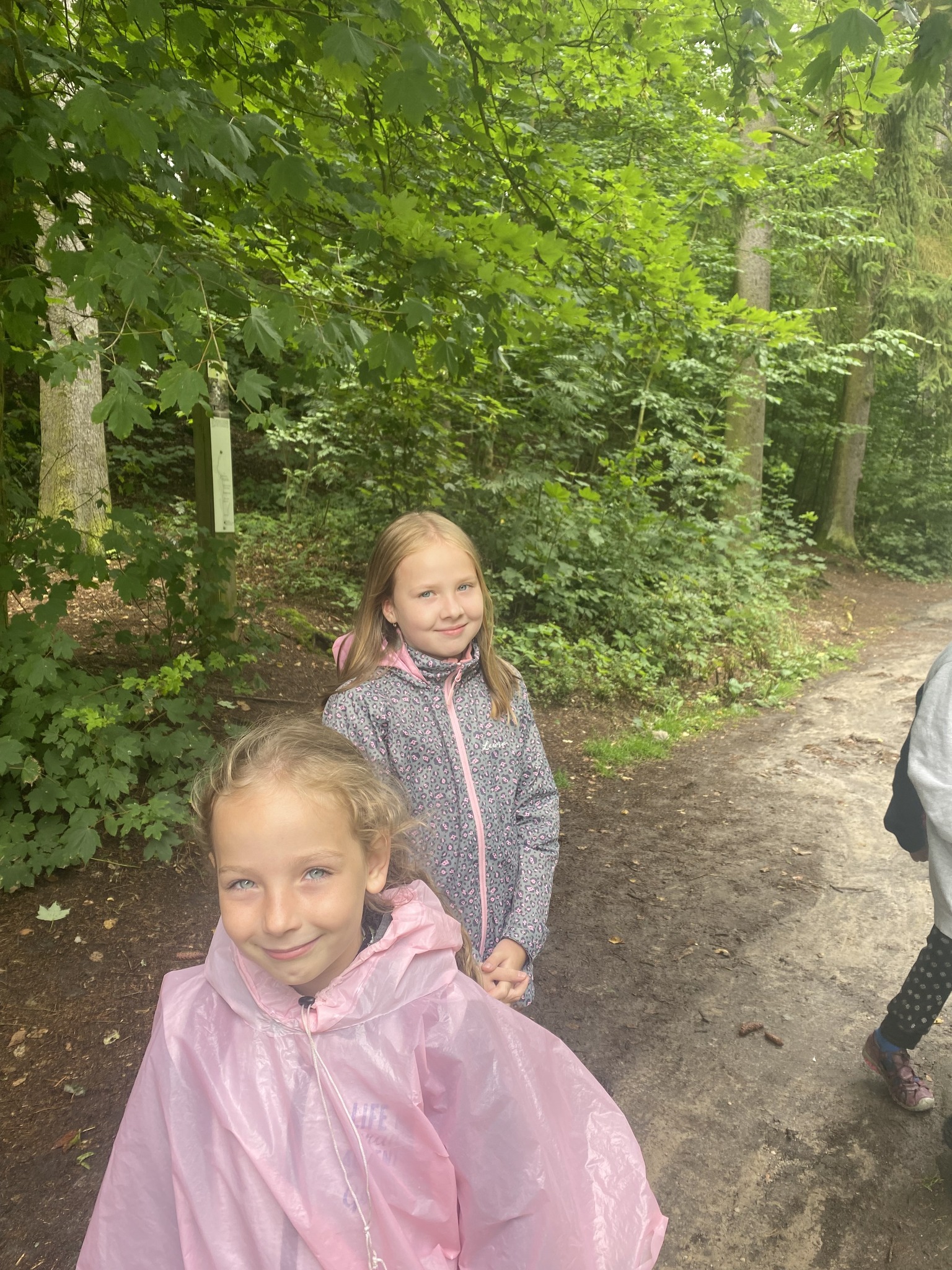 Děti na letním táboře pro nejmenší jdou v pláštěnkách do herny v dešti.