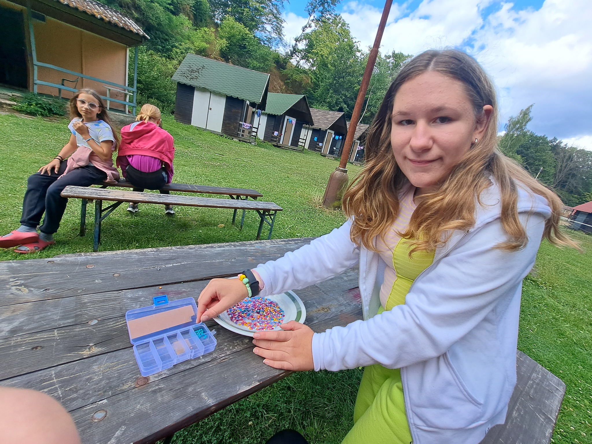 Děti na letním dětském táboře kreslí venku v přírodě poblíž táborové základny.