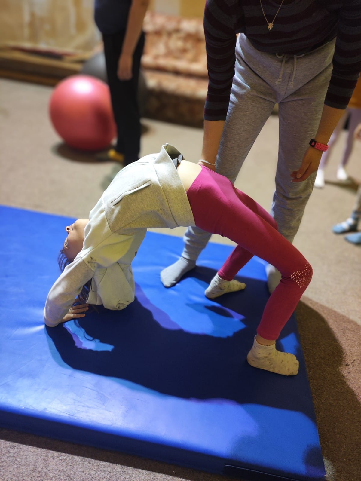Děti na letním dětském táboře cvičí moderní gymnastiku a atletiku v tělocvičně.