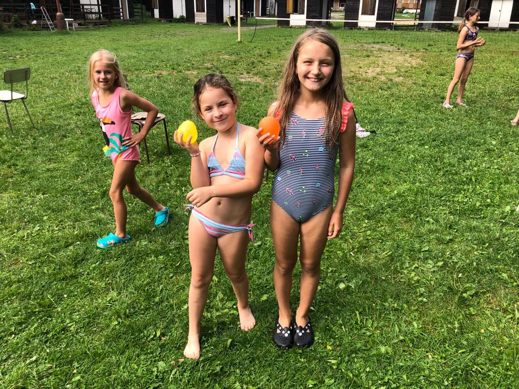 Dívky si hrají s vodou na letním dětském táboře.