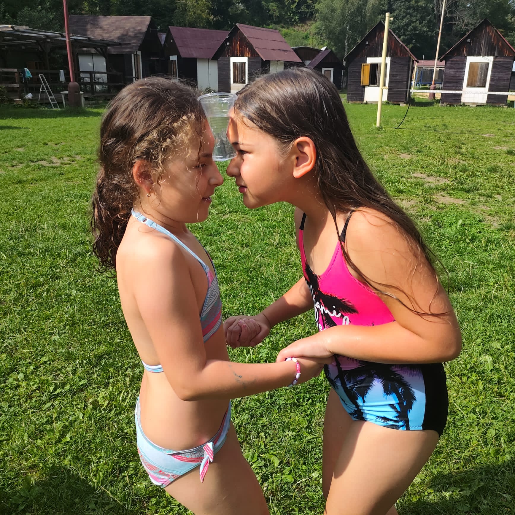 Dívky spolu soutěží na letním táboře a hrají si s vodou.
