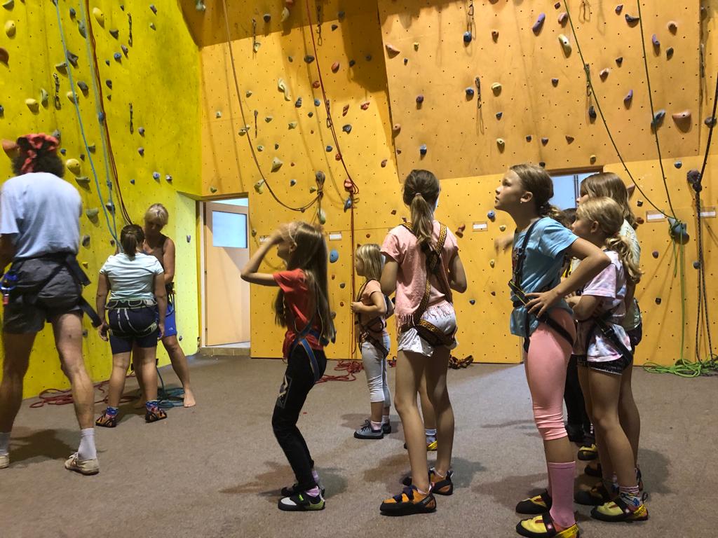 Skupina dětí čeká na lezeckou stěnu na sportovním dětském táboře.