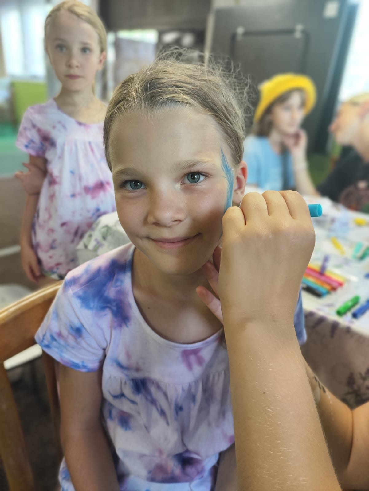 Dívka si maluje na obličej na letním kreativním výtvarném táboře.