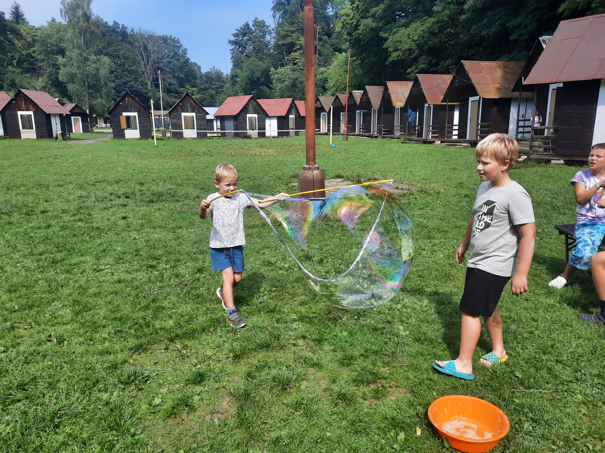 Děti si hrají s velkými bublinami na letním dětské táboře.