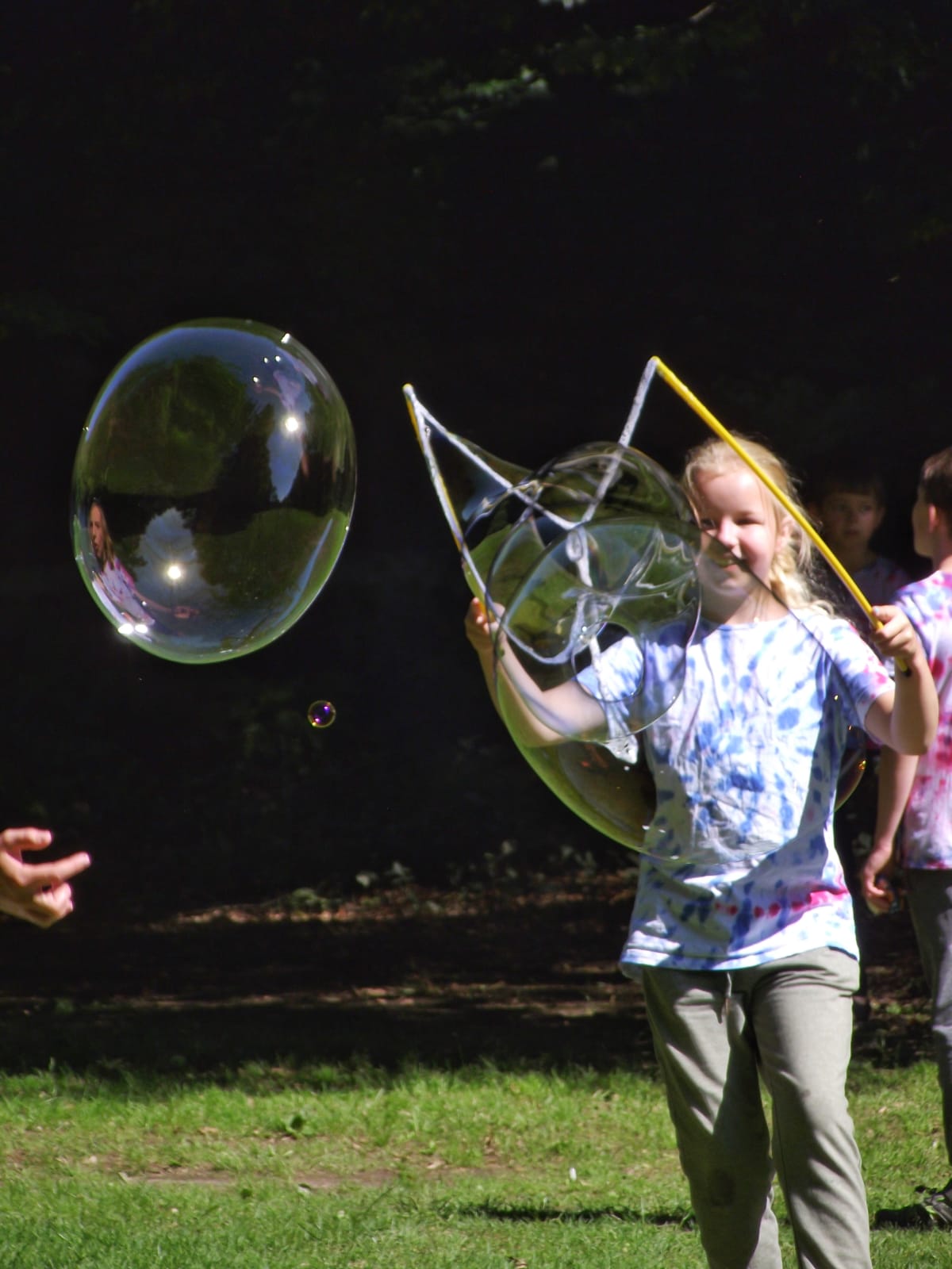 Děti na letním dětském táboře vyrábí velké bubliny a hrají si s bublifuky.