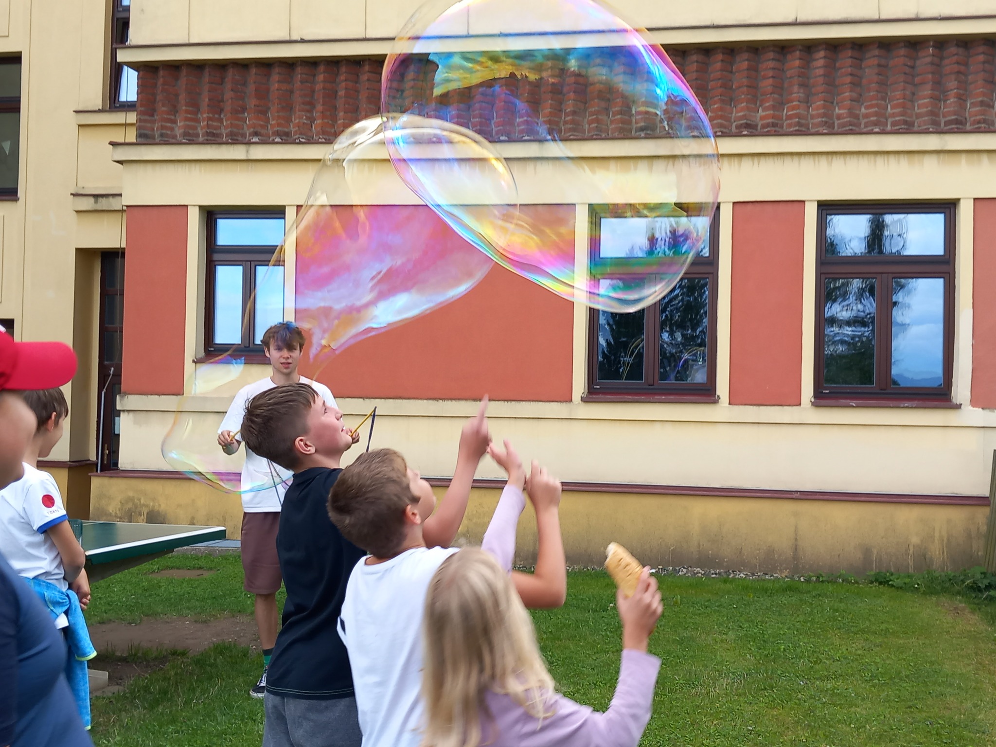 Děti na letním dětské táboře vyrábí velké bubliny v místní škole.