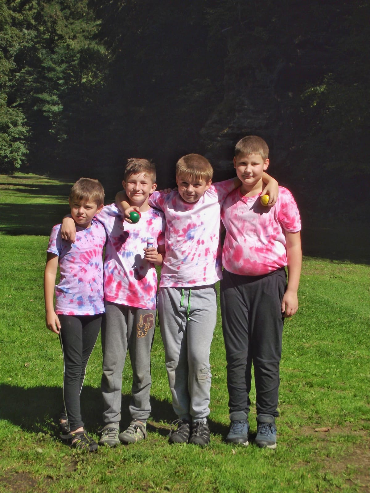Děti na letním kutilském táboře se fotí v přírodě a mají batikovaná trička.
