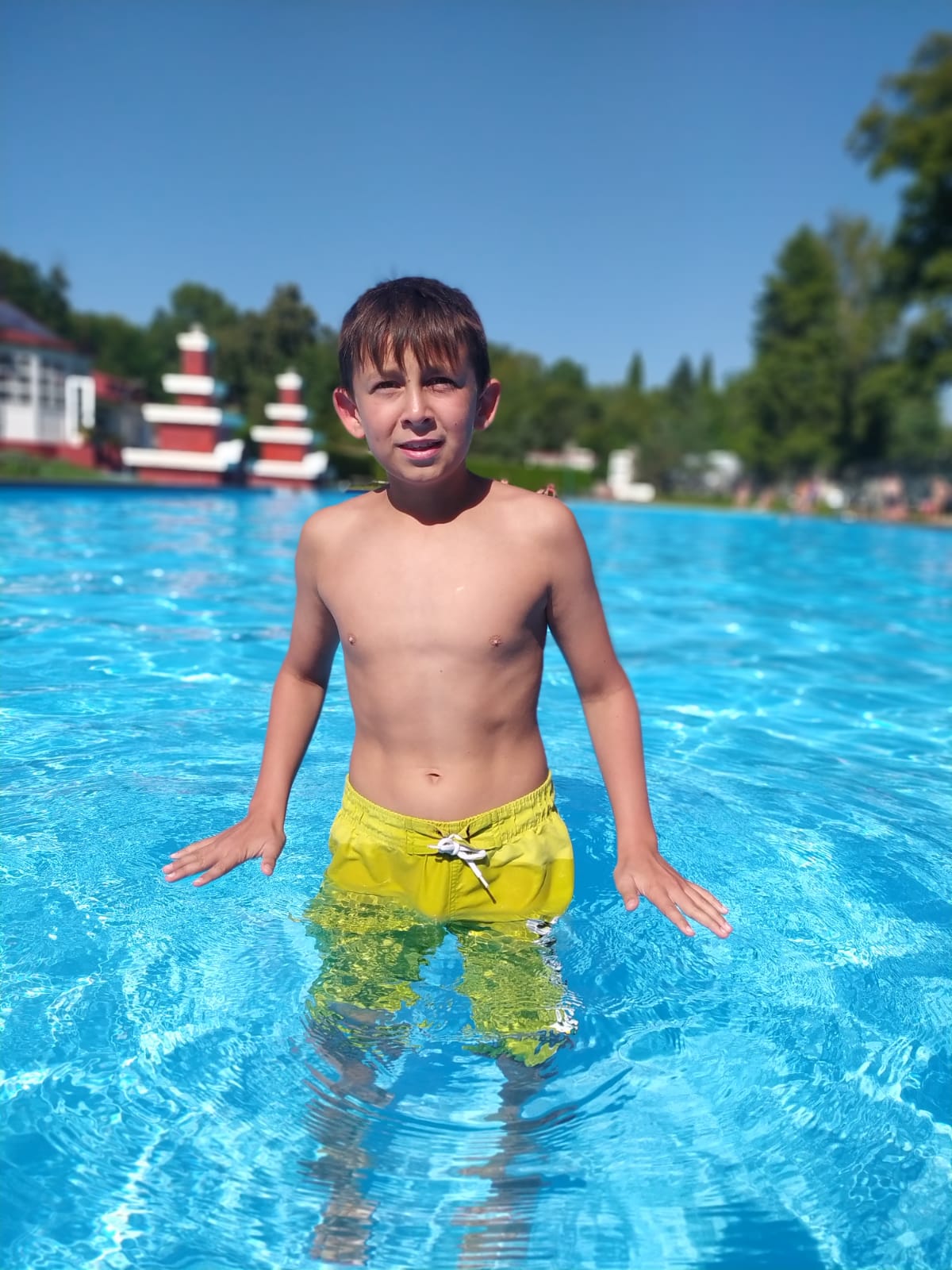 Chlapec na letním dětském táboře se koupe v bazénu a užívá si spoustu zábavy.