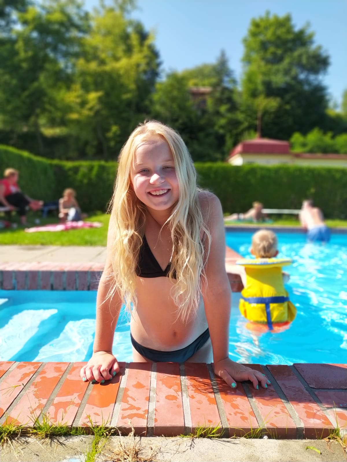 Dívka na letním dětském táboře se koupe v bazénu a užívá si spoustu zábavy.