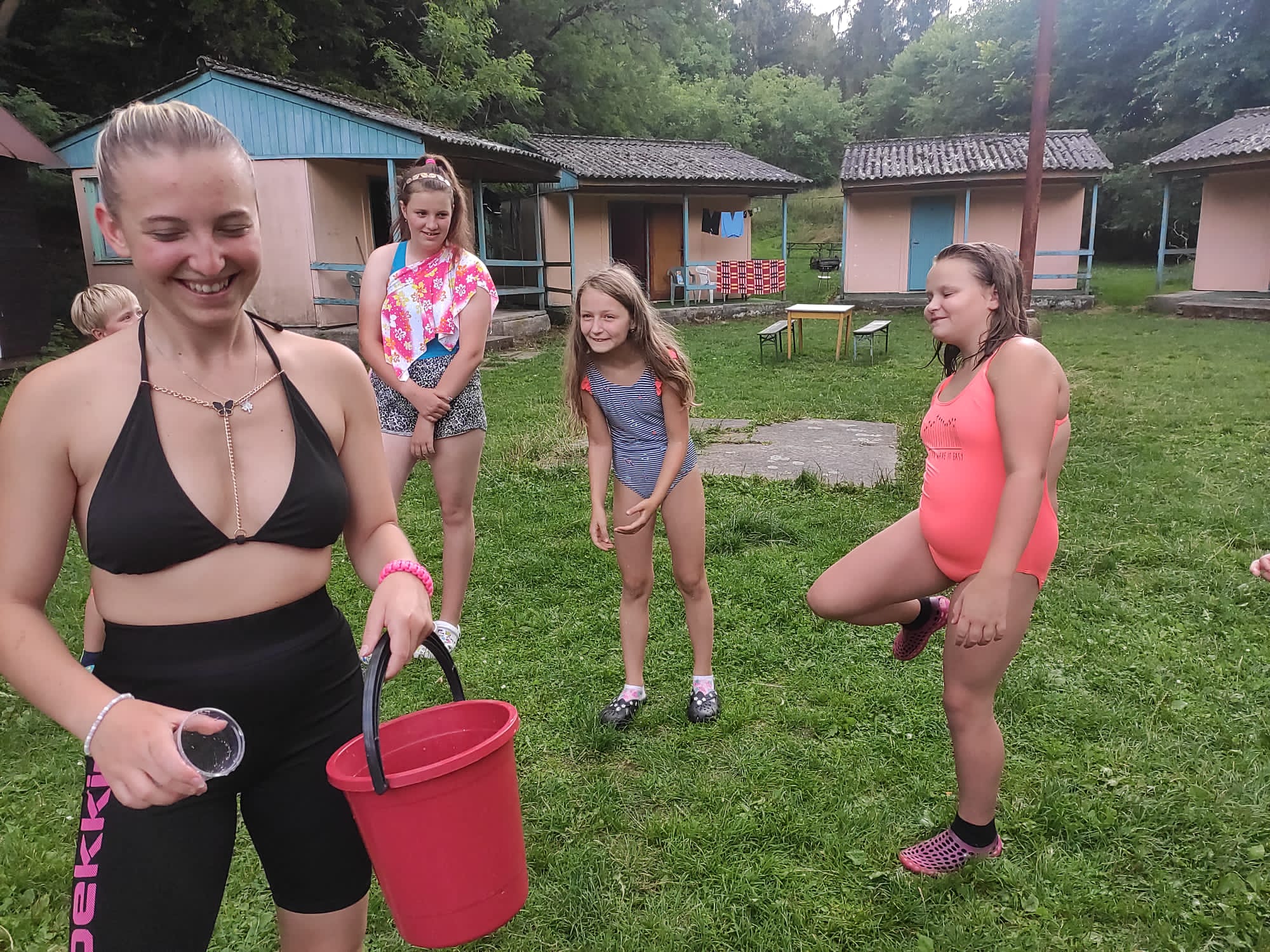 Děti a vedoucí na letním táboře si užívají společnou zábavu a hrají si s balónky a vodou.