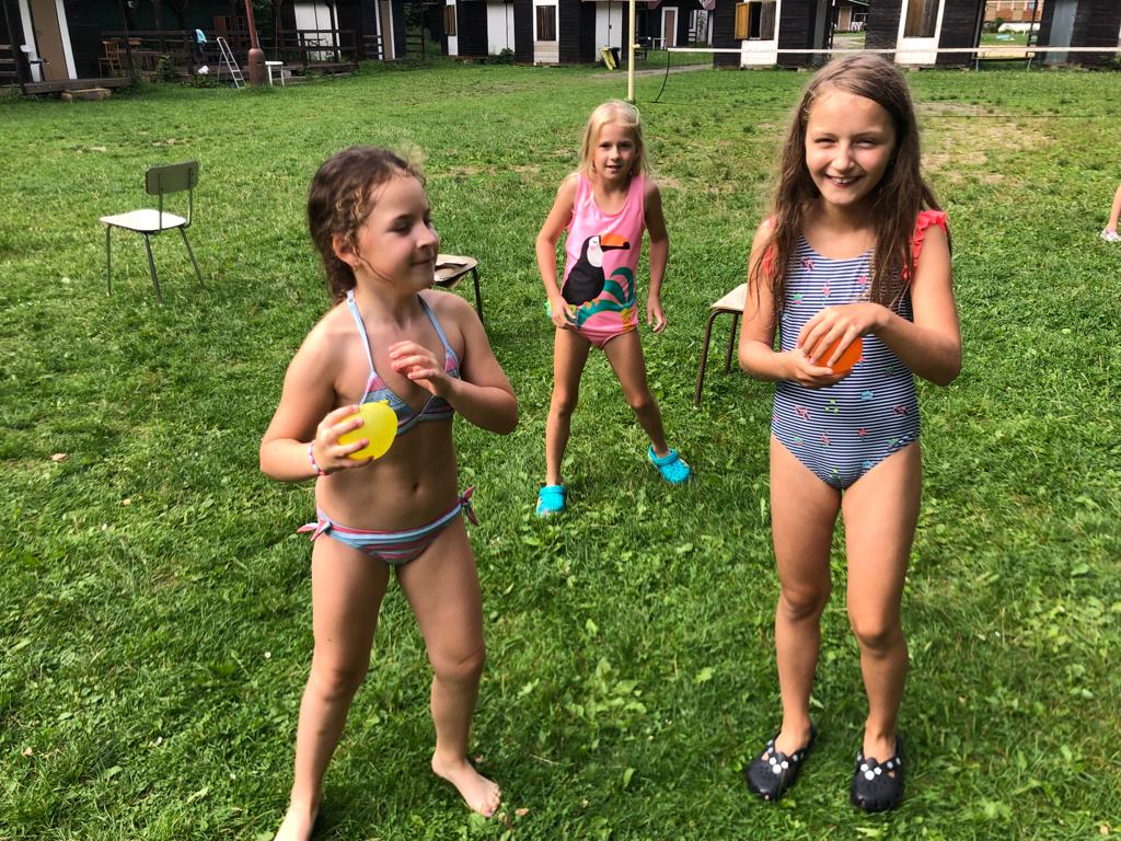Dívky si hrají v plavkách v parném dni s vodou na letním pěveckém táboře.