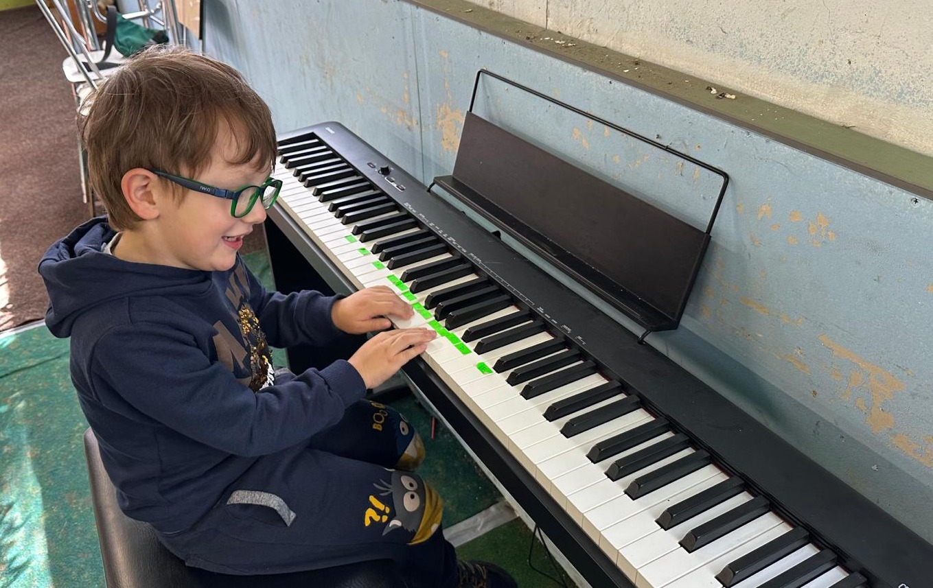 Chlapec hraje na piano na dětském letním hudebním táboře.