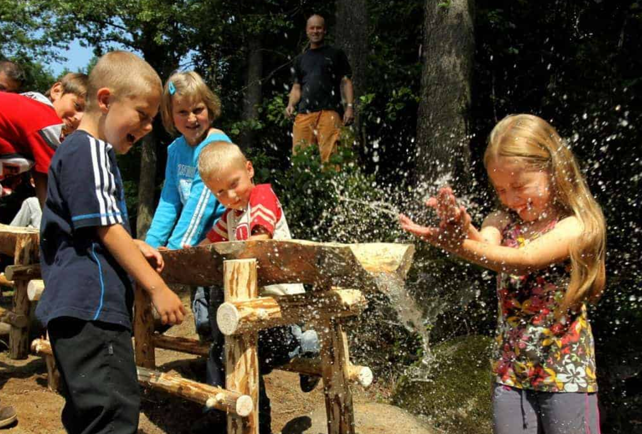 Děti si v létě hrají venku s vodními prvky.